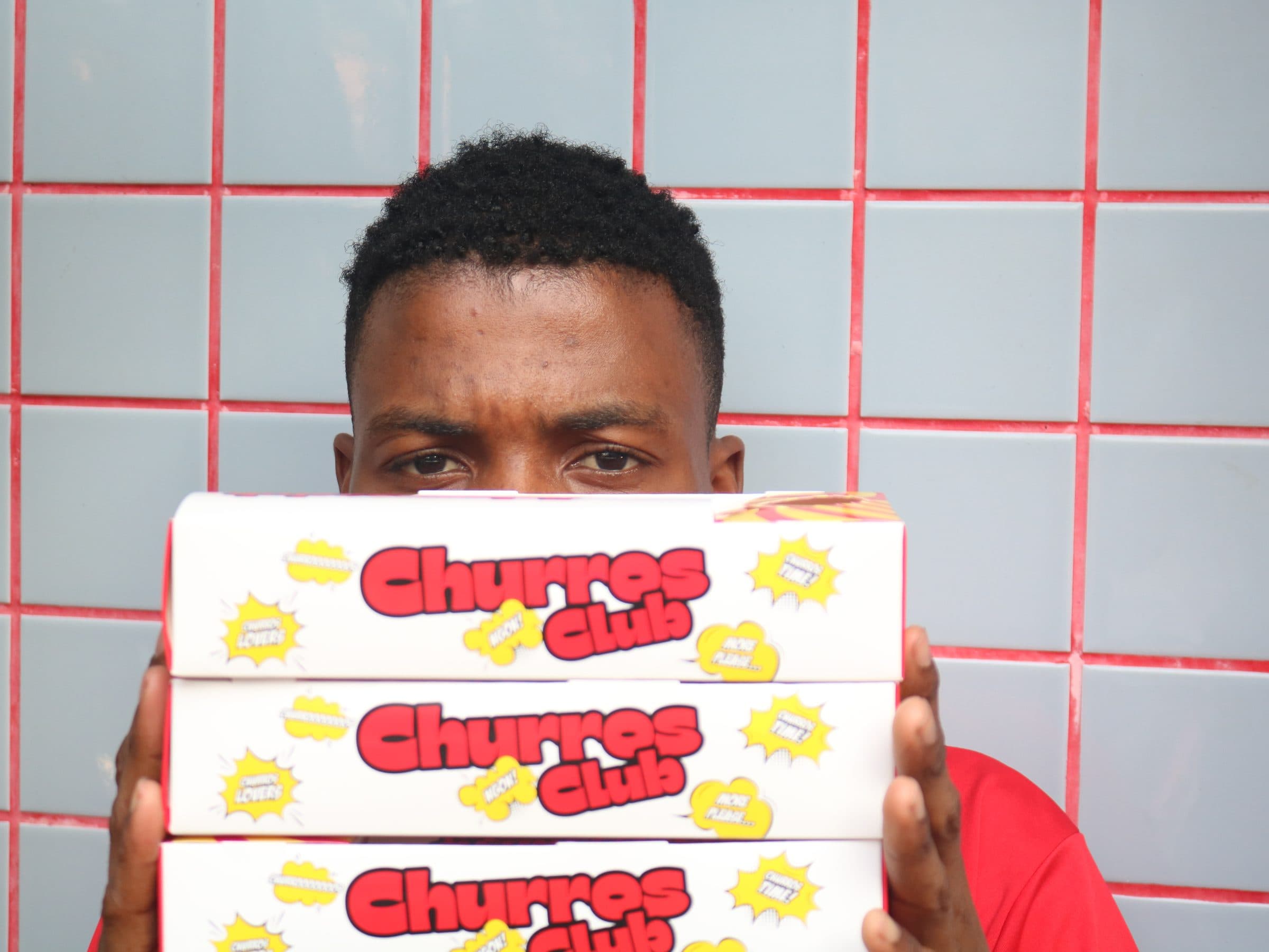 Churros Club staff peeking over a stack of boxes