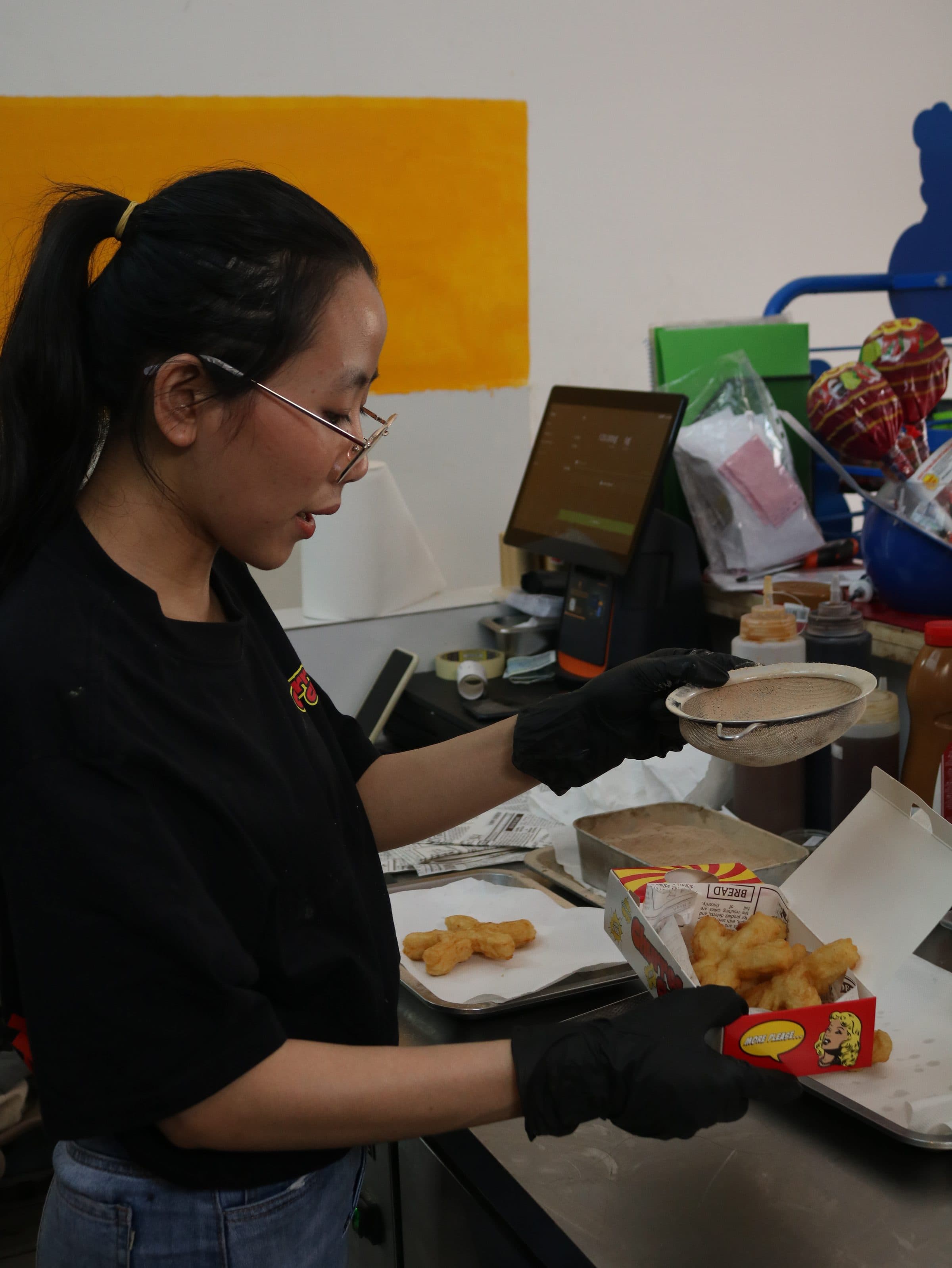 Churros Club staff dusting fresh churros behind the counter