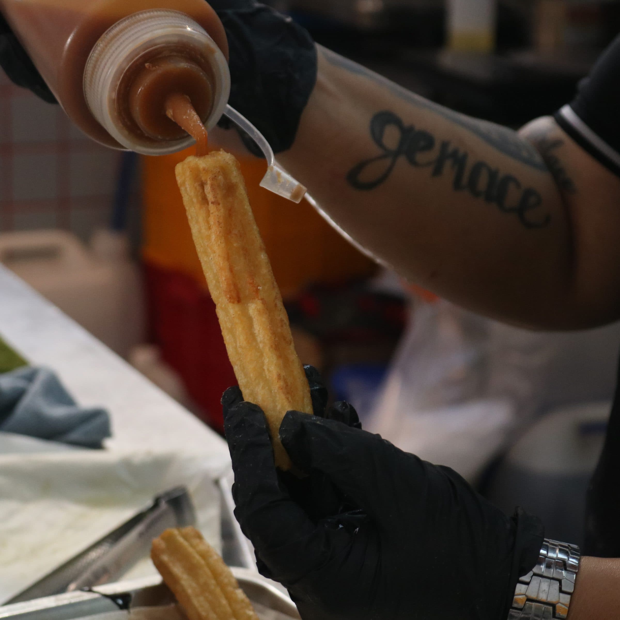 Fresh churro being drizzled with sauce at Churros Club