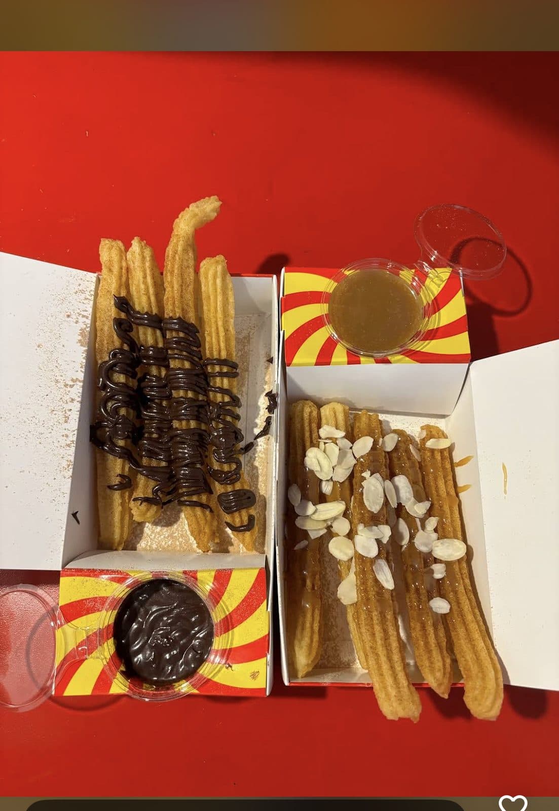 Two boxes of churros with chocolate almond and honey almond toppings